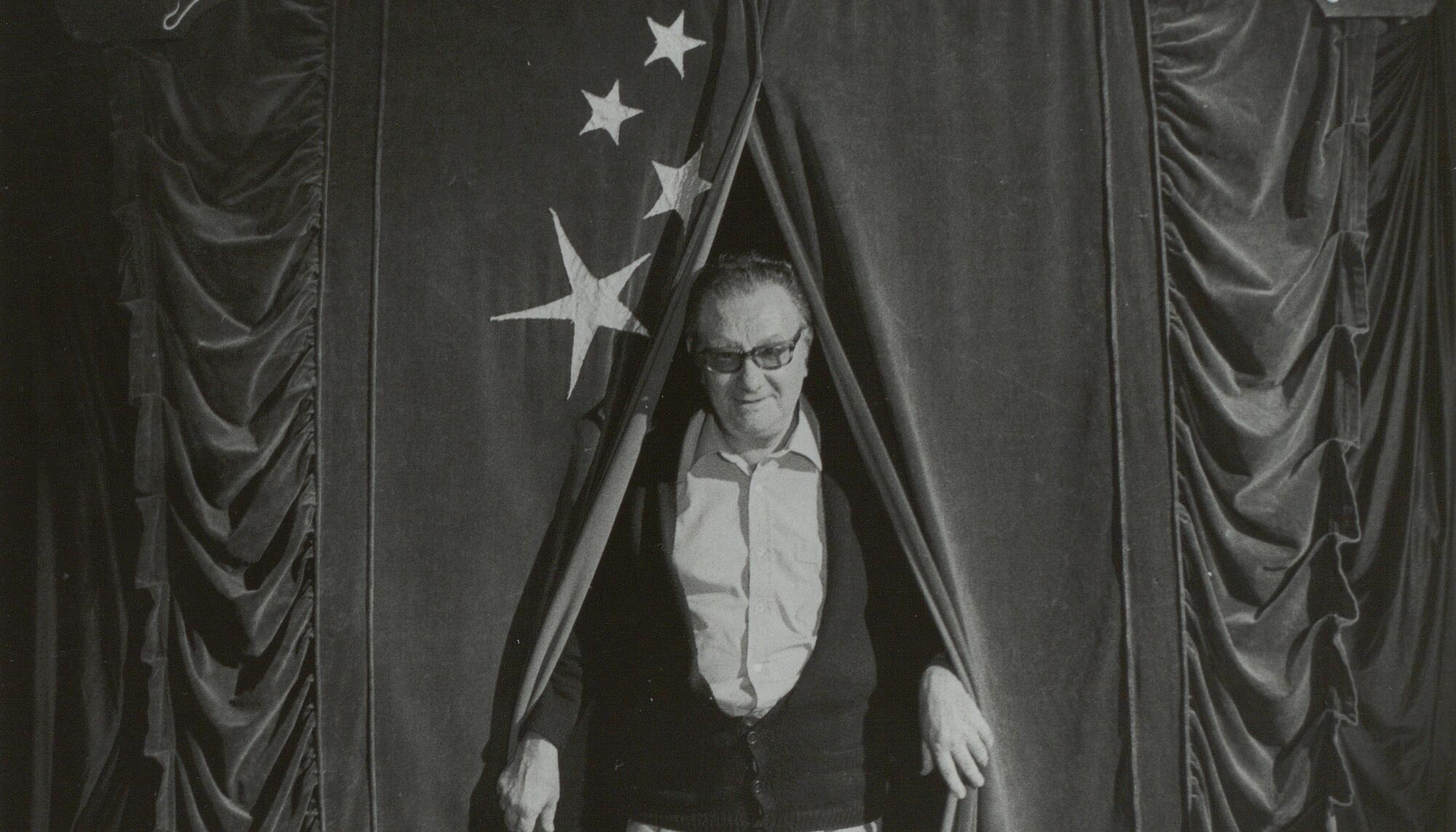 Retrato de Joan Brossa saliendo de un telón de la compañía Circ Perillós