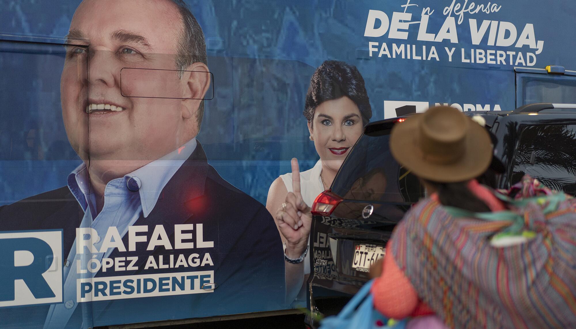 Una mujer con la característica vestimenta de altiplano peruano observa el autobús de propaganda electoral de López Aliaga.