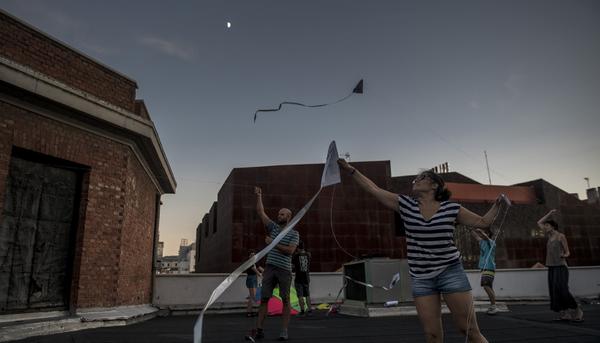 Un grupo de gente volando cometas a la luz del anochecer en la terraza de La Ingobernable