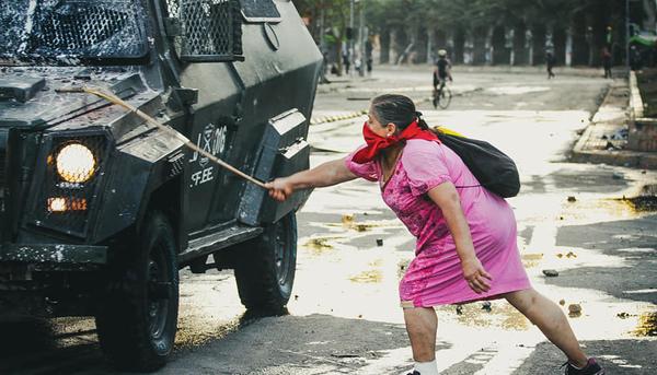 Mujer chilena y carabineros policía, en las protestas contra el gobierno neoliberal de Piñera en Chile, Latinoamérica