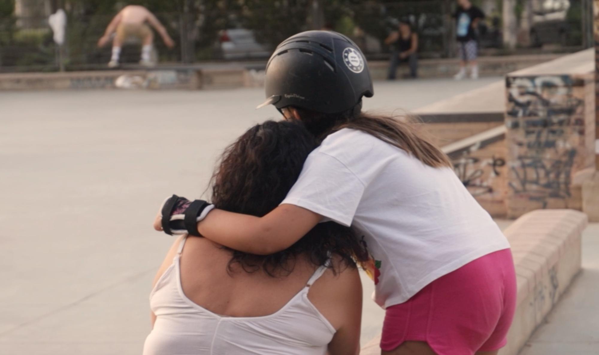 Madre e hija se abrazan en un skatepark