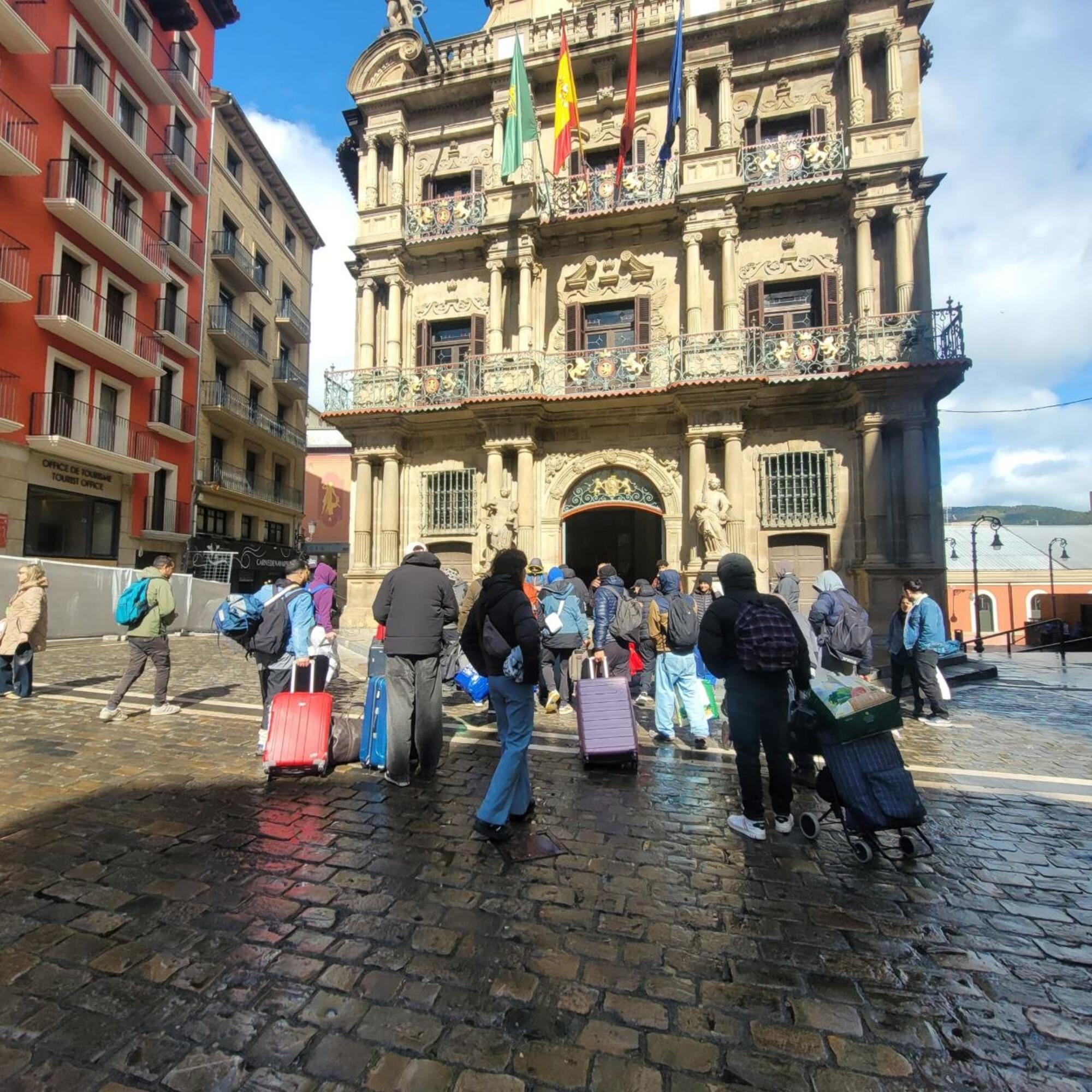 Varias decenas de trabajadores migrantes desalojados de Aranzadi se dirigen al consistorio de Iruñea cargados con sus maletas y enseres