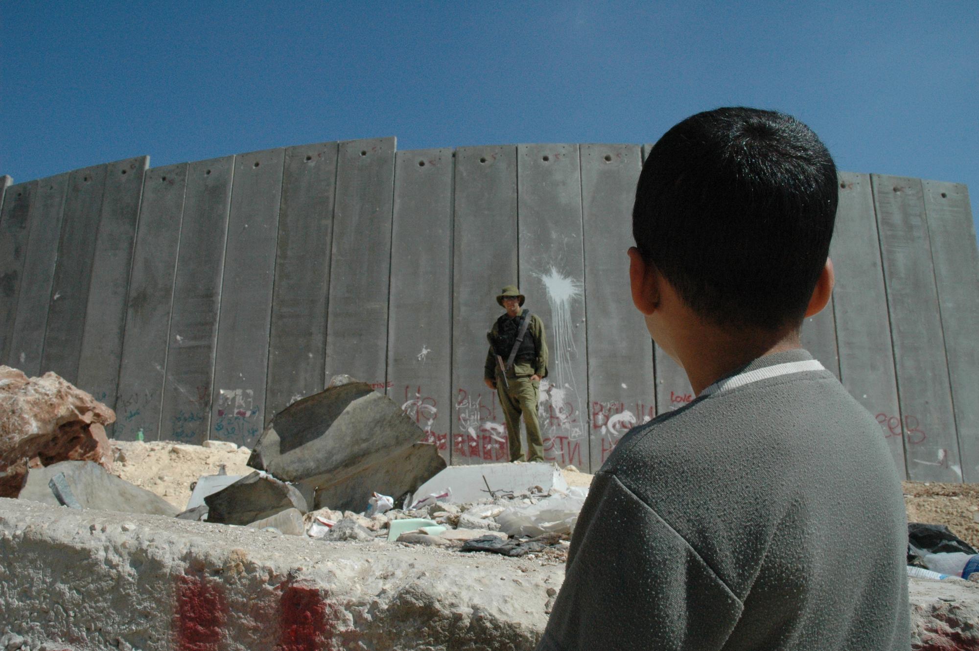 Niño palestino observa a un soldado israelí
