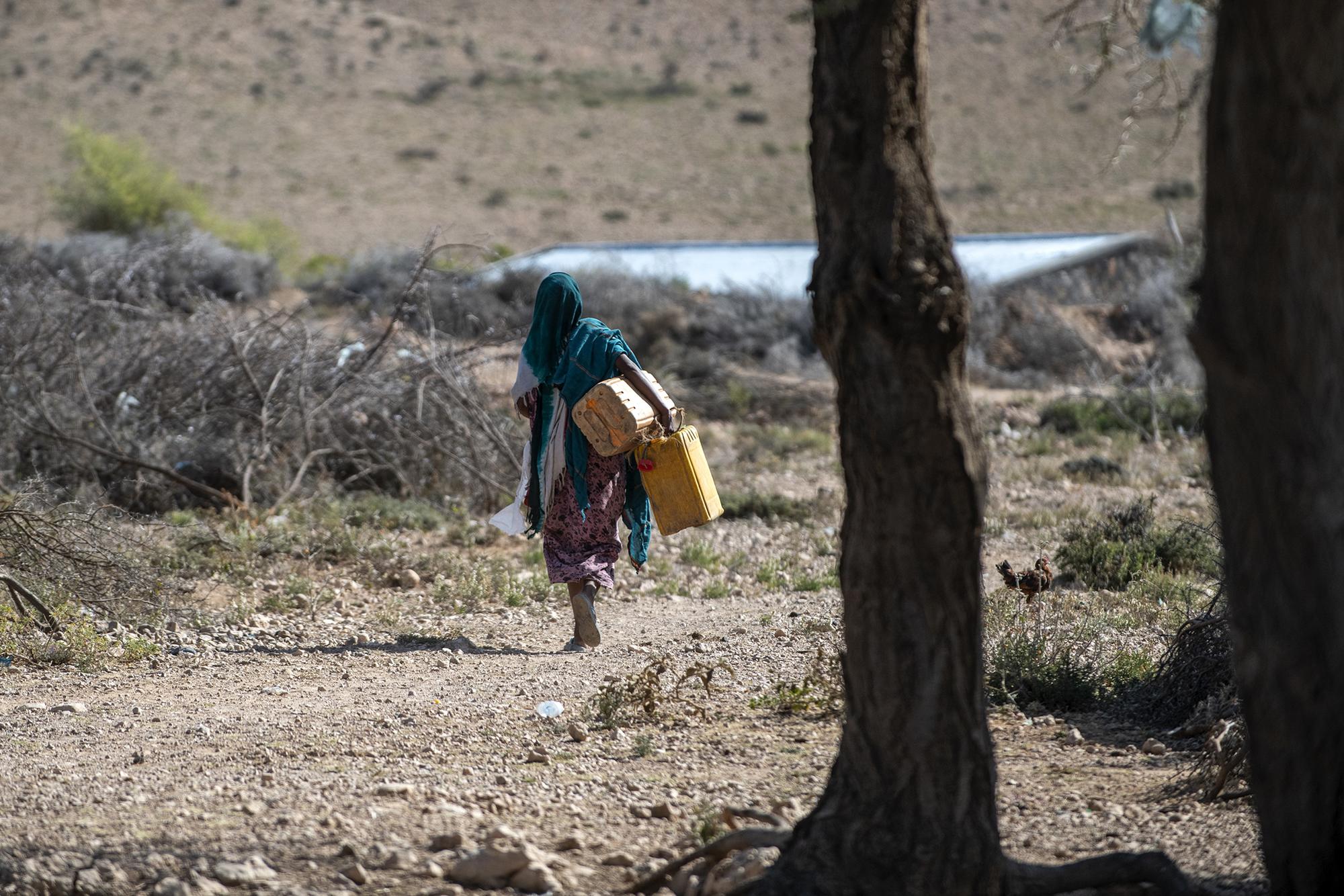 Mujer cargando con bidones de agua